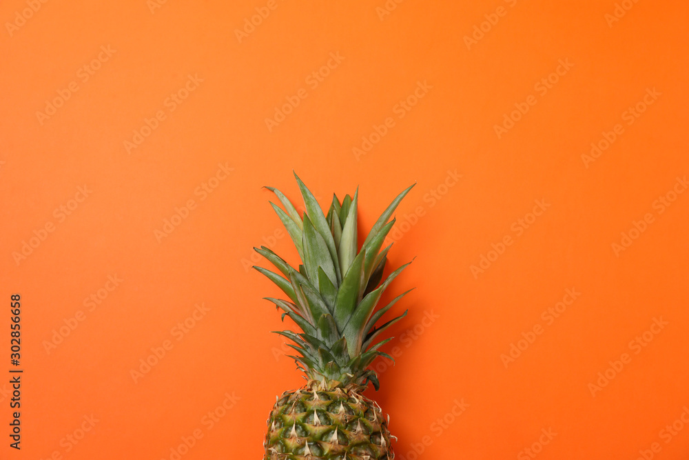Top of pineapple on orange background, space for text. Juicy fruit