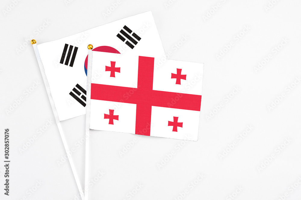 Georgia and South Korea stick flags on white background. High quality fabric, miniature national flag. Peaceful global concept.White floor for copy space.