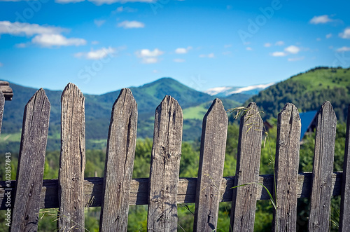 Weathered Timber Picket Fence in the Mountain Village on a Sunny Summer Day. Altai Mountains, Kazakhstan.