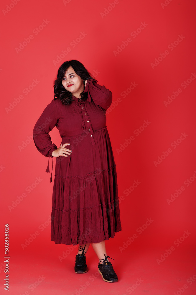 Attractive south asian woman in deep red gown dress posed at studio on pink background. Attractive south asian woman in deep red gown dress posed at studio on pink background.