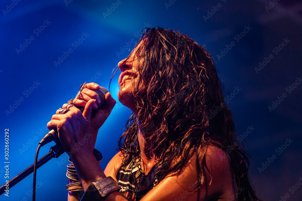 Αυτοκόλλητο A female musician is viewed from a low angle as she sings and smiling with the a