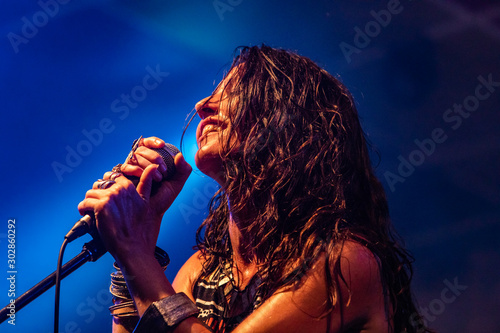 Fotografía A female musician is viewed from a low angle as she sings and smiling with the a