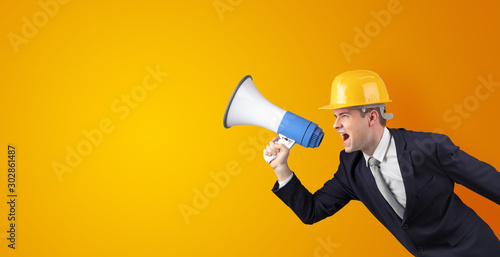 Young architect constructor yelling with megaphone and copyspace