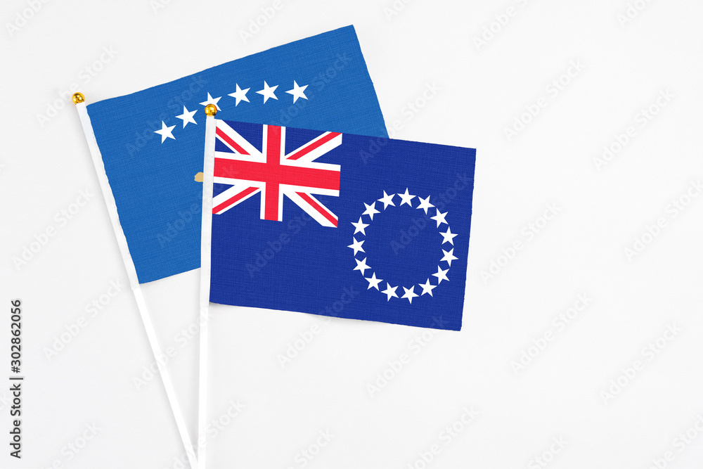 Fototapeta premium Cook Islands and Kosovo stick flags on white background. High quality fabric, miniature national flag. Peaceful global concept.White floor for copy space.