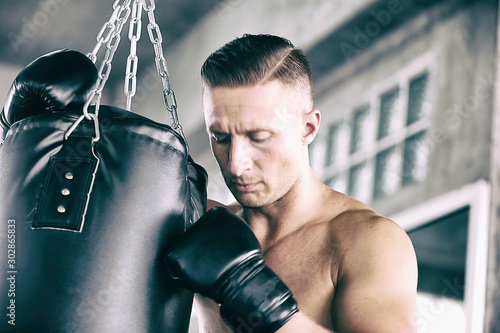 Sportsman muay thai boxer fighting in gloves in boxing cage against fitness gym. Copy Space. photo