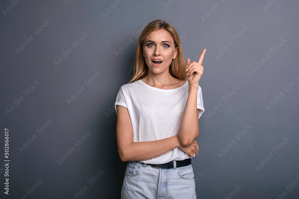Caucasian woman in neutral casual outfit standing on a neutral grey background. Portrait with emotions: happiness, amazement, joy and satisfaction Caucasian woman in neutral casual outfit standing on a neutral grey background. Portrait with emotions: happiness, amazement, joy and satisfaction