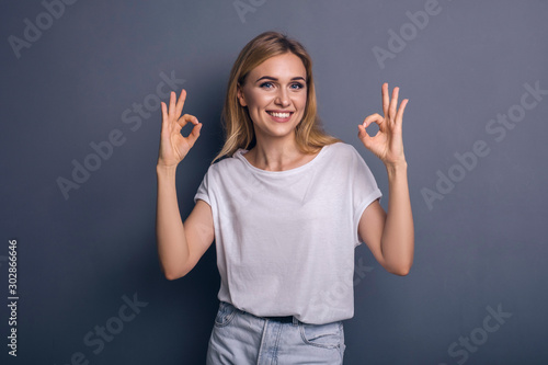 Caucasian woman in neutral casual outfit standing on a neutral grey background. Portrait with emotions  happiness  amazement  joy and satisfaction