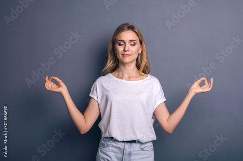Caucasian woman in neutral casual outfit standing on a neutral grey background. Portrait with emotions: happiness, amazement, joy and satisfaction