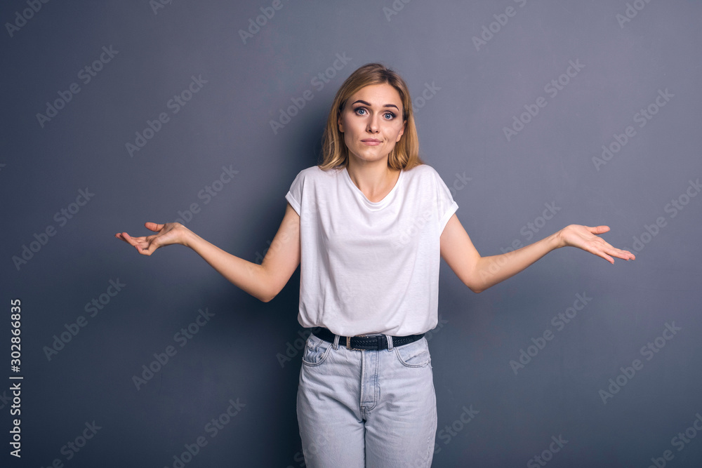 Caucasian woman in neutral casual outfit standing on a neutral grey background. Portrait with emotions: angry, pain, sickness and despair Caucasian woman in neutral casual outfit standing on a neutral grey background. Portrait with emotions: angry, pain, sickness and despair