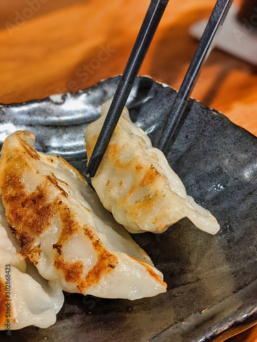 Chopsticks picking up a pork gyoza dumpling at a Japanese restaurant photo