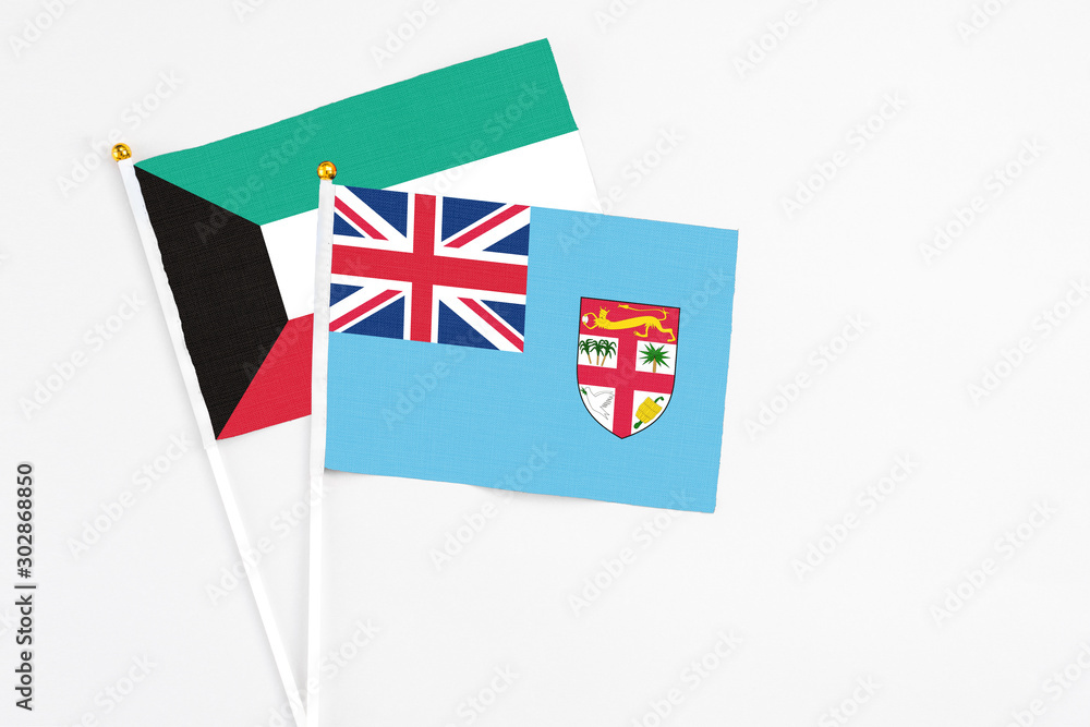 Fototapeta premium Fiji and Kuwait stick flags on white background. High quality fabric, miniature national flag. Peaceful global concept.White floor for copy space.