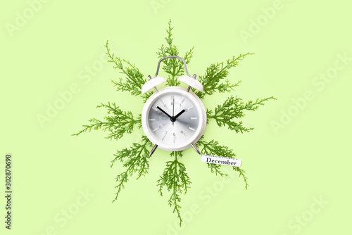 A white alarm clock on a juniper branches