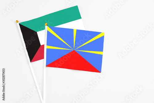 Reunion and Kuwait stick flags on white background. High quality fabric, miniature national flag. Peaceful global concept.White floor for copy space.