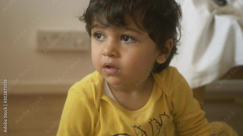 Toddler baby boy with brown eyes in a yellow shirt looking staring off camera Toddler baby boy with brown eyes in a yellow shirt looking staring off camera