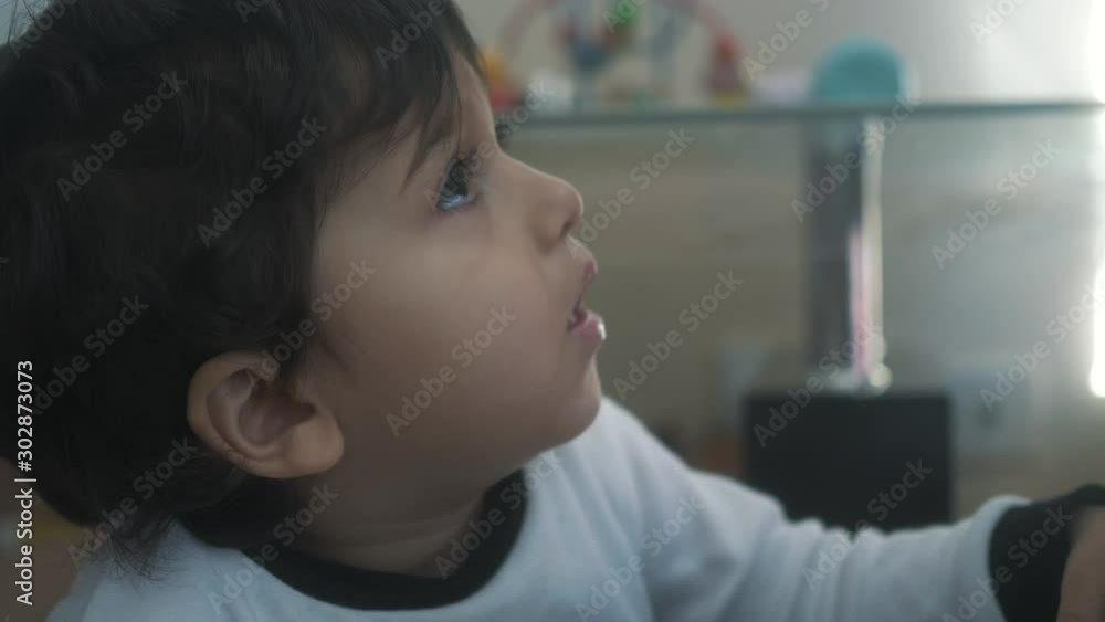 Candid close up of young toddler boy looking up at home in living room