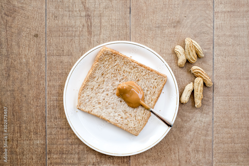 a classic slice of whole wheat bread with smooth peanut butter on wooden background a classic slice of whole wheat bread with smooth peanut butter on wooden background