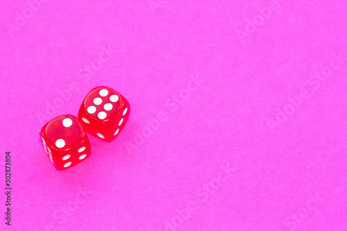 Gambling dices on a pink background.