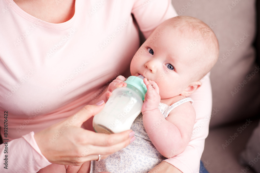 Mother feeding baby with fresh milk on hands in room. Motherhood. Maternity. Mother feeding baby with fresh milk on hands in room. Motherhood. Maternity.