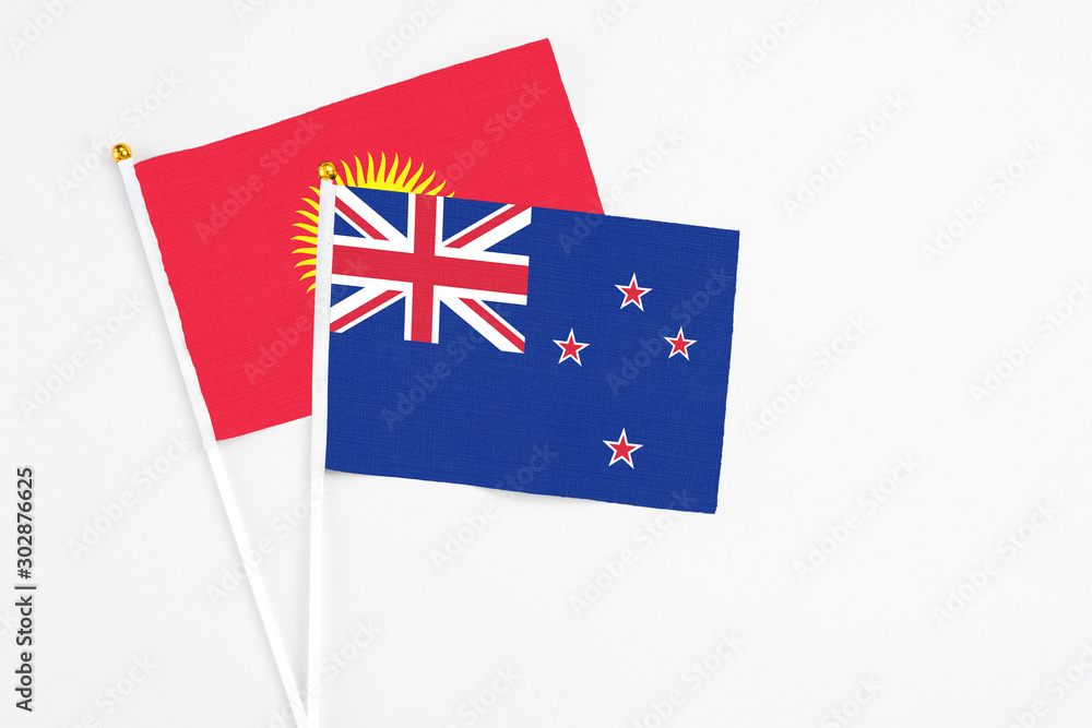 Fototapeta premium New Zealand and Kyrgyzstan stick flags on white background. High quality fabric, miniature national flag. Peaceful global concept.White floor for copy space.