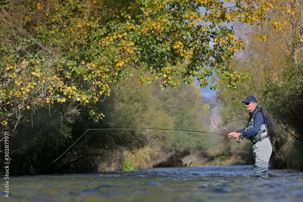 fly fisherman in autumn and fast river