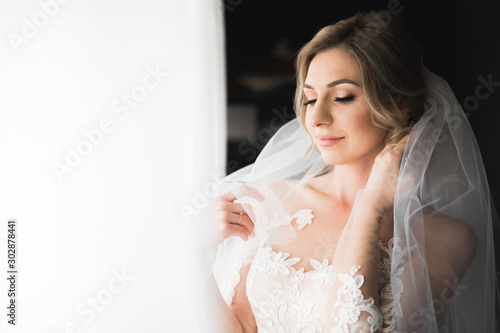 Beauty portrait of bride wearing fashion wedding dress with feathers with luxury delight make-up and hairstyle