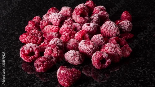 Amazing defrost process of rasperries on black surface,close up time lapse photo