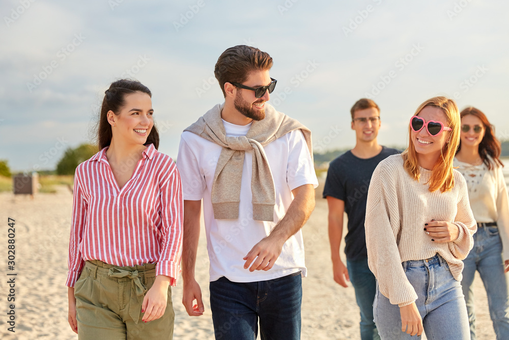 © Syda Productions - friendship, leisure and people concept - group of happy friends walking along beach in summer