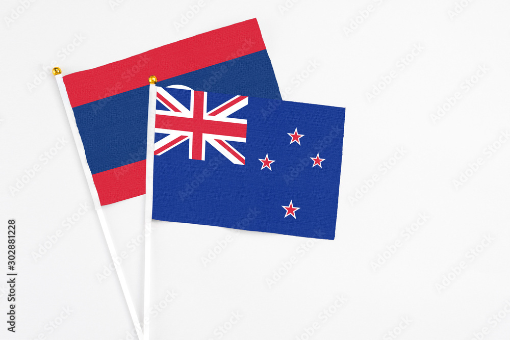 Fototapeta premium New Zealand and Laos stick flags on white background. High quality fabric, miniature national flag. Peaceful global concept.White floor for copy space.