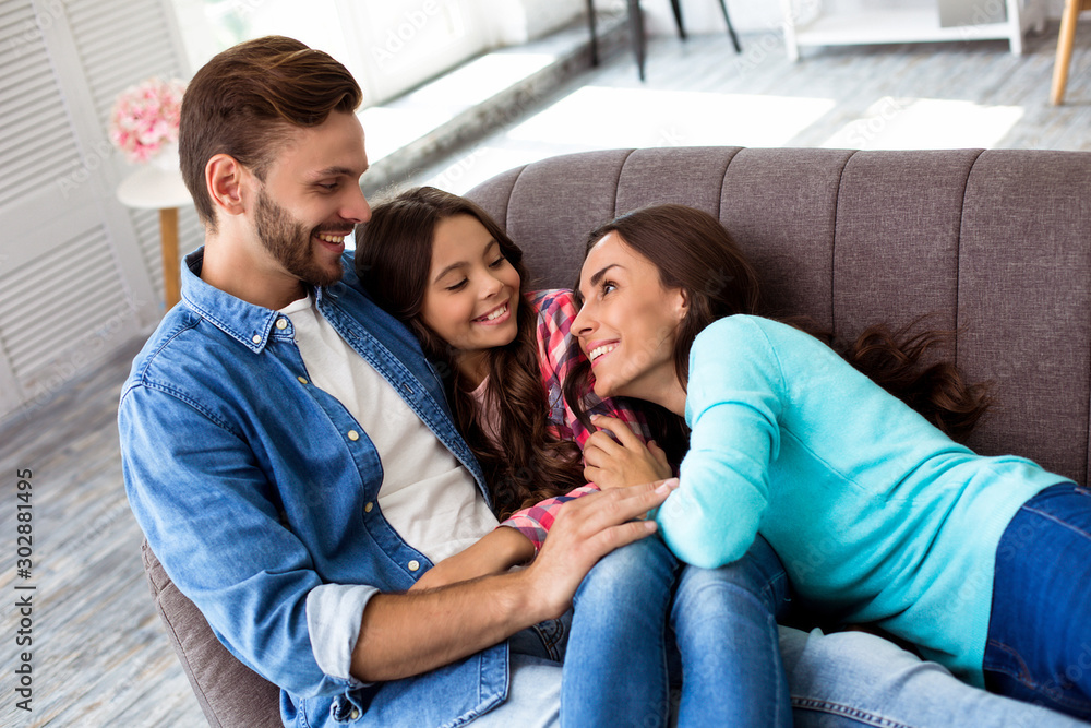 Sweet memories. Three family members are lying on the couch together, cuddling and laughing with joy while looking into each other’s eyes. Sweet memories. Three family members are lying on the couch together, cuddling and laughing with joy while looking into each other’s eyes.