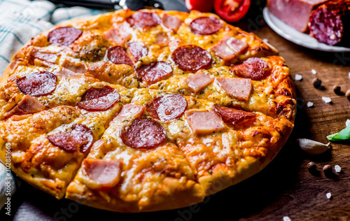 Pepperoni Pizza with Mozzarella cheese, salami, ham. Italian pizza on wooden table background