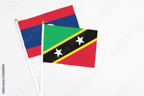 Free Download Saint Kitts And Nevis and Laos stick flags on white background. High quality fabric, miniature national flag. Peaceful global concept.White floor for copy space. - GFXLoad
