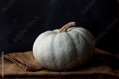 Still life of light pumpkin lies on a rough brown bag for vegetables on a black background view from the side closeup.