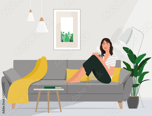 A young woman is resting in a cozy living room with a cup of tea after work.