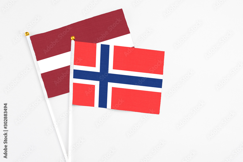 Bouvet Islands and Latvia stick flags on white background. High quality fabric, miniature national flag. Peaceful global concept.White floor for copy space.