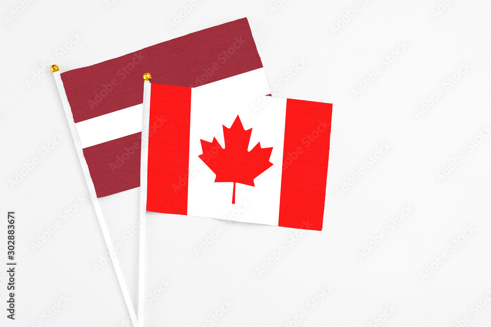 Canada and Latvia stick flags on white background. High quality fabric, miniature national flag. Peaceful global concept.White floor for copy space. Canada and Latvia stick flags on white background. High quality fabric, miniature national flag. Peaceful global concept.White floor for copy space.