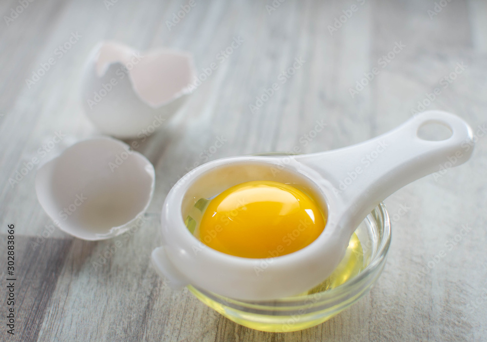 Separated egg white and yolk, egg shell on wooden table Separated egg white and yolk, egg shell on wooden table