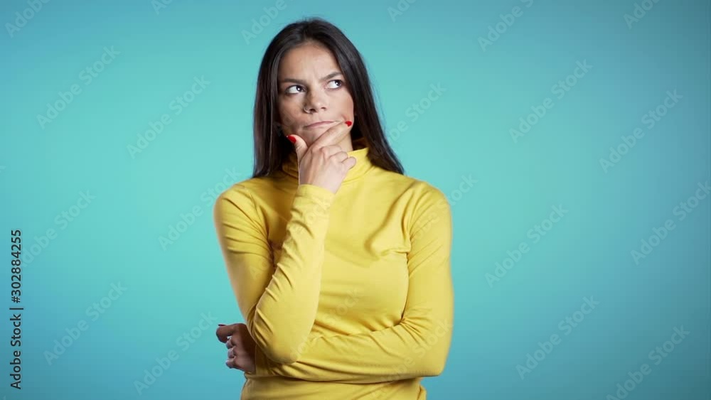Thinking woman looking up and around on blue background. Worried contemplative face expressions. Beautiful young hispanic model. Thinking woman looking up and around on blue background. Worried contemplative face expressions. Beautiful young hispanic model.