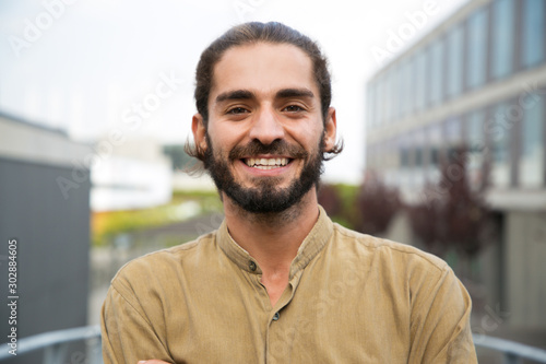 Handsome happy bearded man. Portrait of cheerful young man standing outdoors and smiling at camera. Emotion concept photo