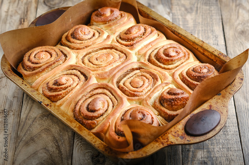 Fresh homemade cinnabons baked in metal form on a light rustic background top view. Homemade baking. photo