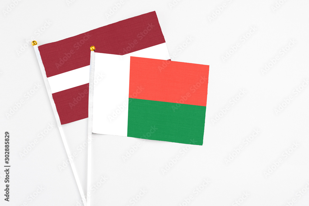 Madagascar and Latvia stick flags on white background. High quality fabric, miniature national flag. Peaceful global concept.White floor for copy space. Madagascar and Latvia stick flags on white background. High quality fabric, miniature national flag. Peaceful global concept.White floor for copy space.