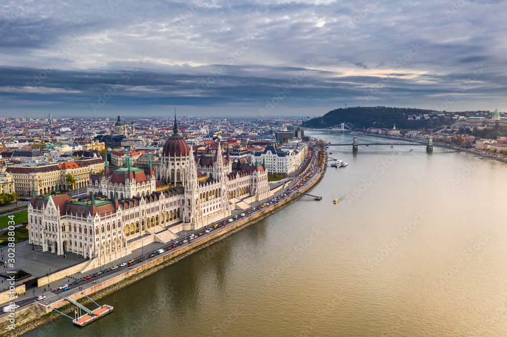Budapest, Hungary - Aerial view of the beautiful Parliament of Hungary at sunset with golden lights and sightseeing boats on River Danube. Szechenyi Chain Bridge, St. Stephen's Basilica at background