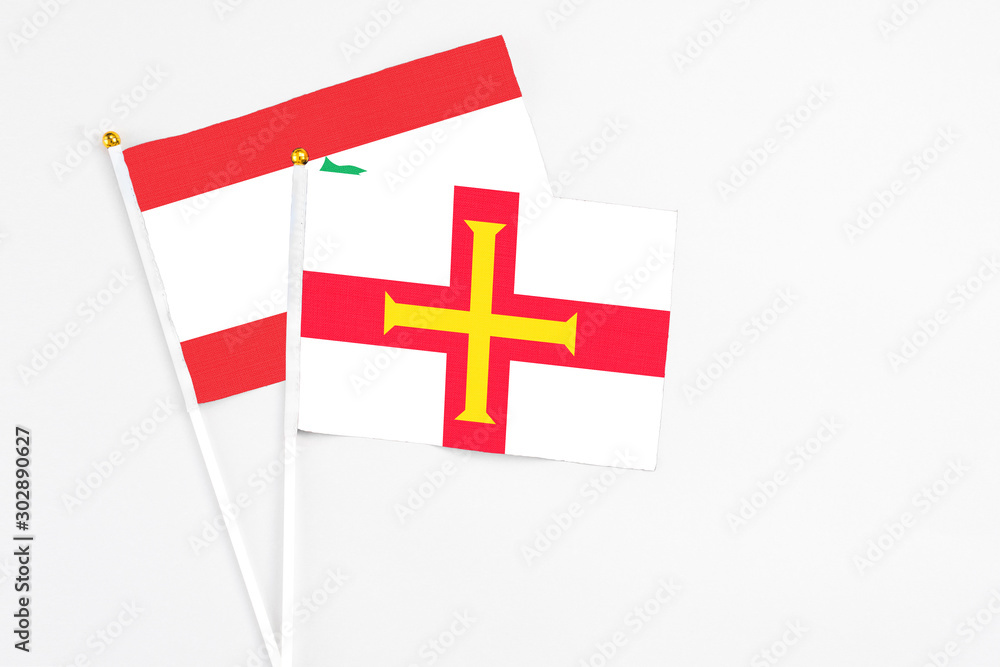 Guernsey and Lebanon stick flags on white background. High quality fabric, miniature national flag. Peaceful global concept.White floor for copy space.