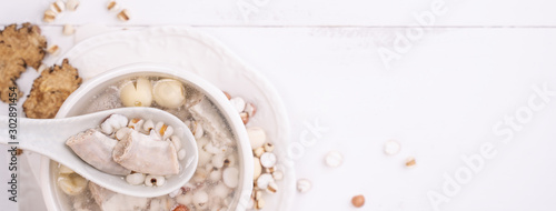 Obraz na plátně Tasty Four Tonics Herb Flavor Soup, Taiwanese traditional food with herbs, pork intestines on white wooden table, close up, flat lay, top view