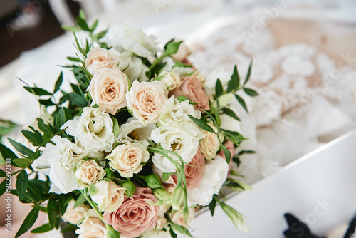 Close up of bridal bouquet of beige and pink roses with wedding dress on background  copy space. Wedding concept