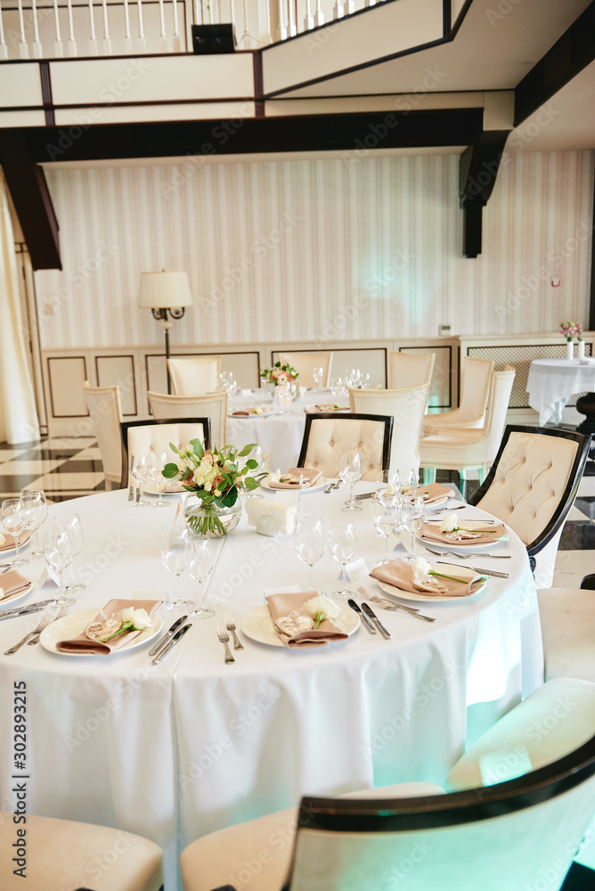 Table setting with blank guest card, white plate with beige serviette, rose, heart and cutlery on table, copy space. Place setting at wedding reception. Table served for wedding banquet in restaurant