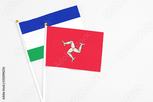 Isle Of Man and Lesotho stick flags on white background. High quality fabric, miniature national flag. Peaceful global concept.White floor for copy space.