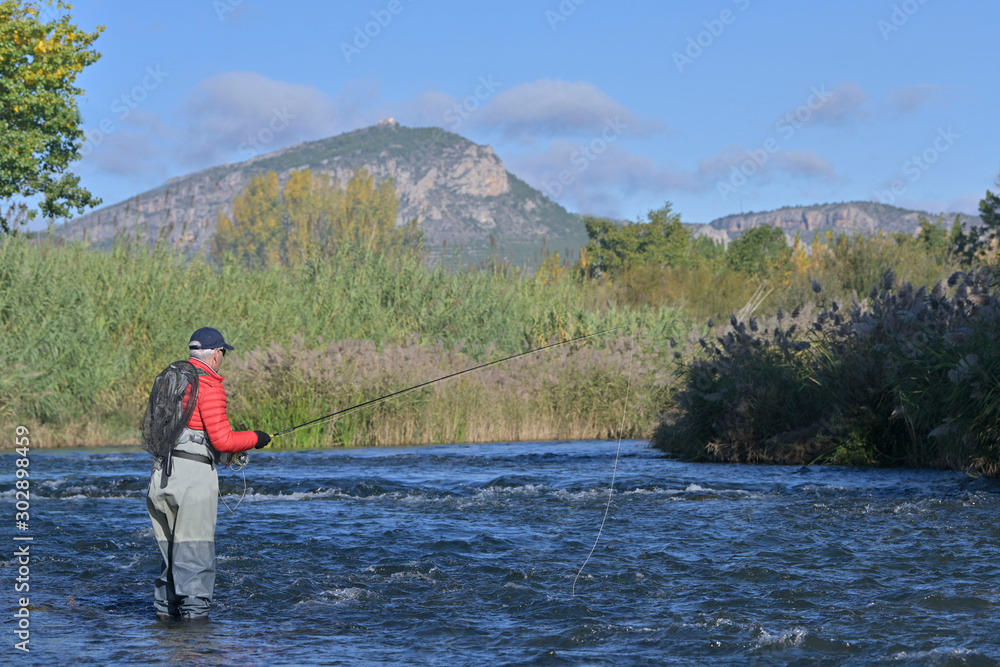 fly fisherman in autumn and fast river