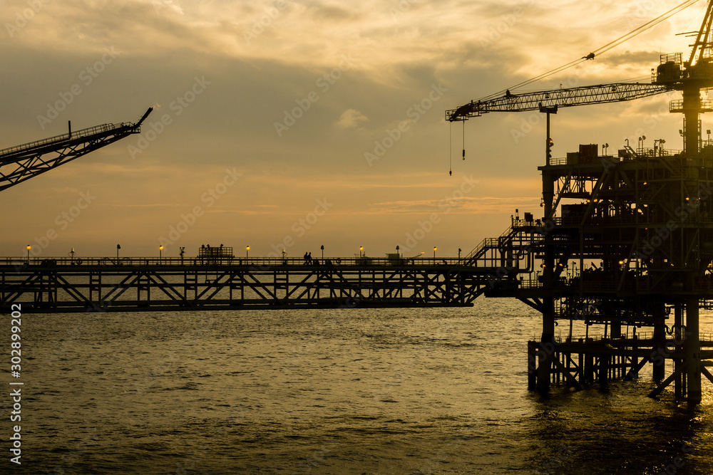 Silhouette of oil production platform during sunset at oil field