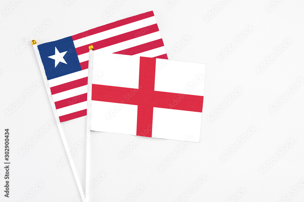 England and Liberia stick flags on white background. High quality fabric, miniature national flag. Peaceful global concept.White floor for copy space.