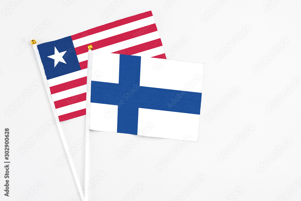 Finland and Liberia stick flags on white background. High quality fabric, miniature national flag. Peaceful global concept.White floor for copy space. Finland and Liberia stick flags on white background. High quality fabric, miniature national flag. Peaceful global concept.White floor for copy space.